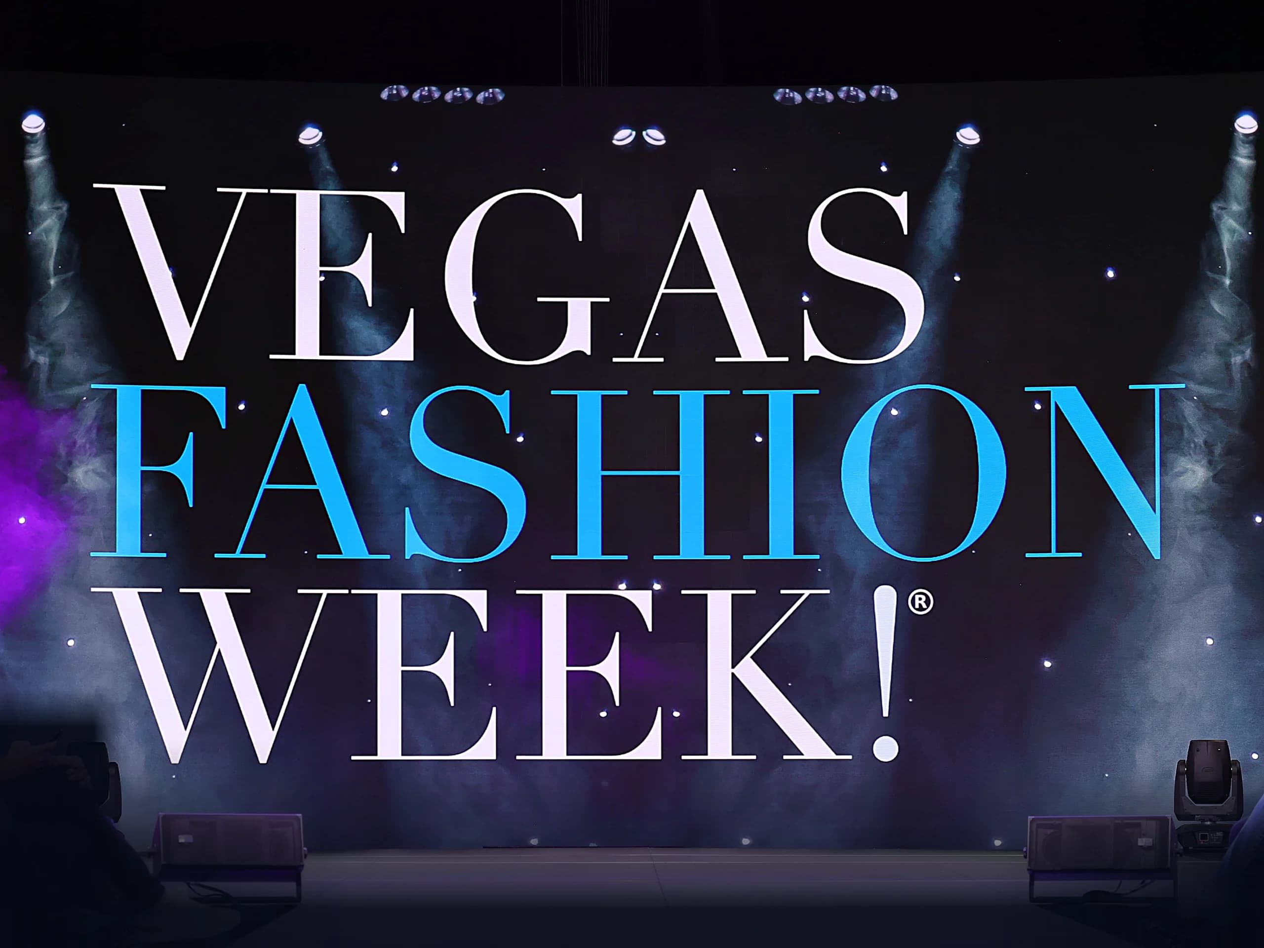 The Vegas Fashion Week® name on a stage screen, under spotlights