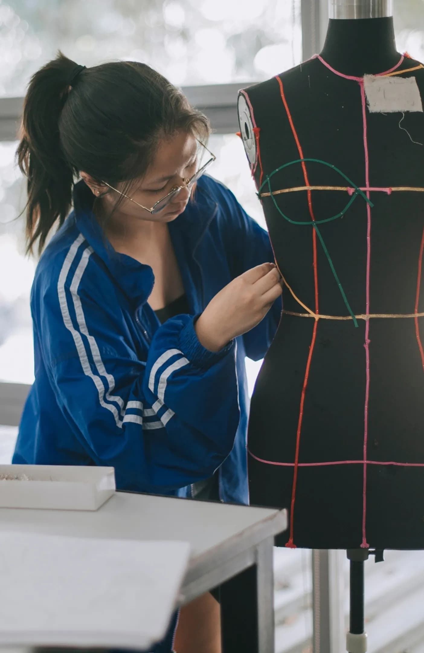 A design student draping fabric on a dress form